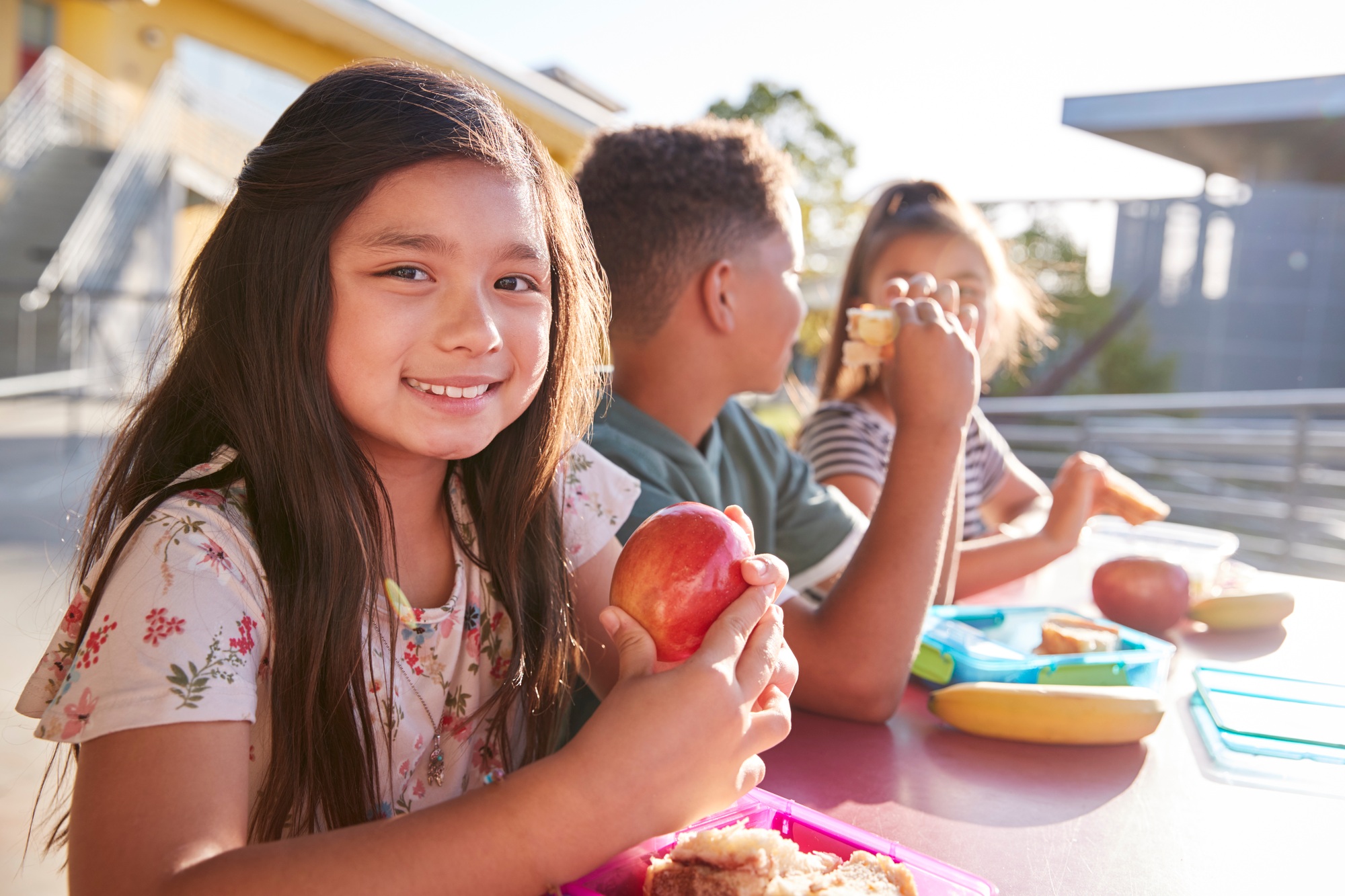 Girl at elementary school lunch table smiling to camera